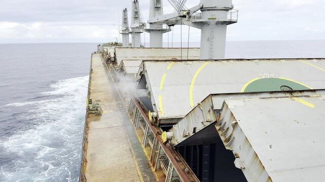 view of bulk carrier ship at sea. daily works of the crew. maintenance hatch covers of cargo holds by high pressure water blaster.