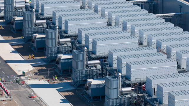 Aerial view of Datacenter Westpoort featuring rows of industrial cooling units and metal infrastructure with a worker on site in Groningen, Groningen, Netherlands.