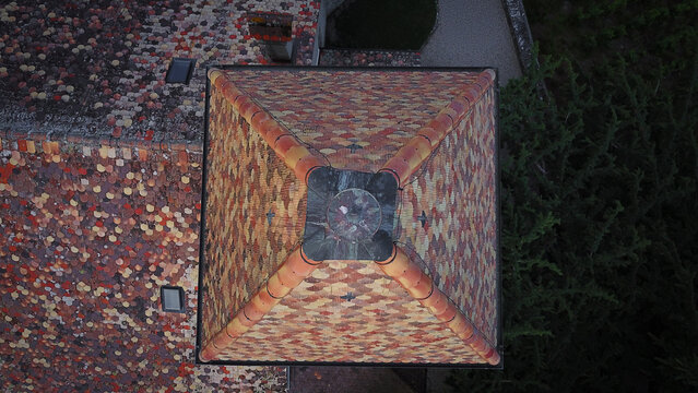 Aerial view of the colorful patterned tile roof of the historic Temple de Luins tower with mosaic shingles in Luins, Vaud, Switzerland.