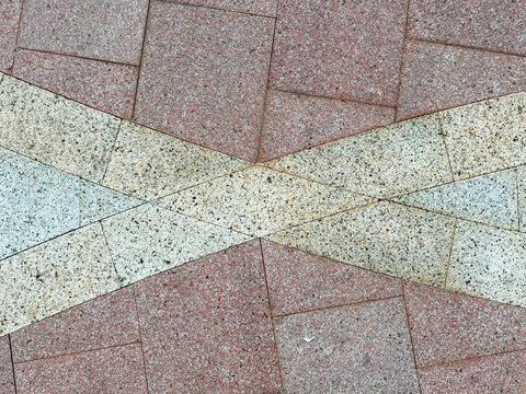 Close up of pink and beige paving stone with interlocking X  pattern. Commonly found in outdoor pavement or exterior sidewalk. Seamless background texture.