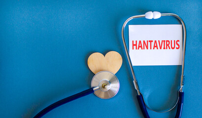 Naklejka premium Hantavirus medical words symbol. Concept words Hantavirus on beautiful white card. Beautiful blue background. Stethoscope. Wooden heart. Medical Hantavirus concept. Copy space.