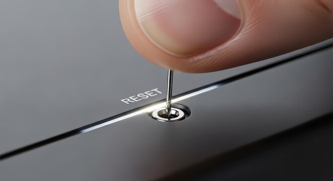 Finger uses a small metal tool to press a recessed reset button on a electronic device.