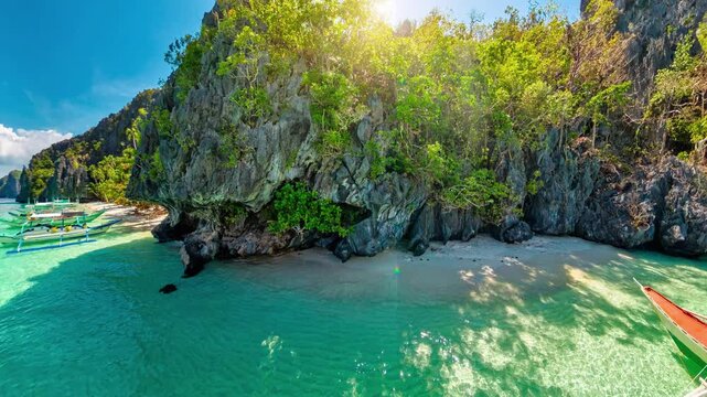 360 view of White sand beach at Entalula, El Nido, Palawan with swaying palms, turquoise water, traditional bangka boats and dramatic limestone karsts beneath a blue sky with clouds in Philippines,