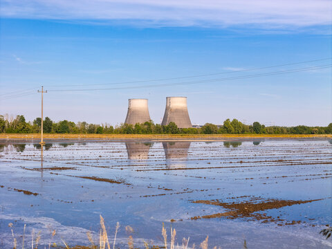 Aerial view of cooling towers of a power plant reflecting in flooded rice paddies under a clear blue sky Livorno Ferraris, Piemonte, Italy.