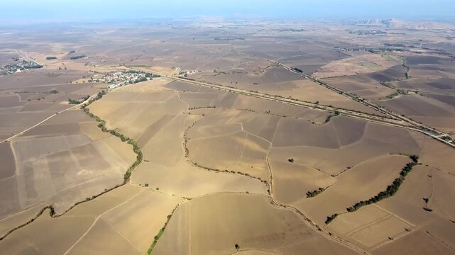 Panoramic aerial view of villages spread across brown agricultural fields on flat alluvial plain. Rural Central Anatolia landscape shows scattered settlements and open lowrelief terrain in Turkey.