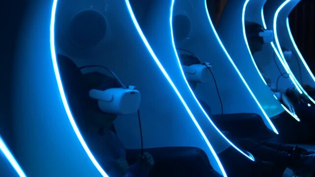 Row of people sitting in individual futuristic pods, each wearing a virtual reality headset and immersed in a digital experience while surrounded by glowing blue neon lights