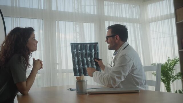 Doctor explaining lumbar spine MRI scan to patient in clinic