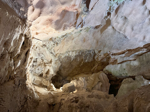 Magnificent cave walls and ceiling texture displaying stalactites and stalagmites with karst and natural limestone rock formations carved by nature.