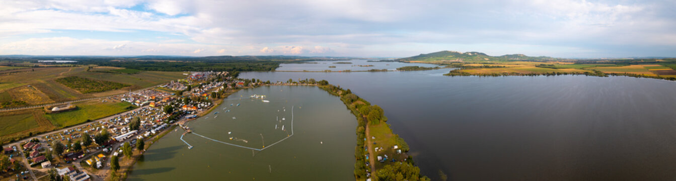 Panoramic aerial view of Nov&eacute; Ml&yacute;ny reservoir and Pasohl&aacute;vky recreation area in South Moravia, Czech Republic during a sunny summer day with fields and calm water.
