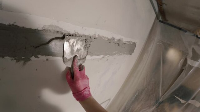 Applying plaster to damaged wall corner with trowel