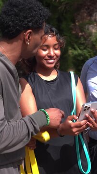 Multiethnic group of athletic friends smiling and taking a selfie with a smartphone after exercising together in a park on a sunny day