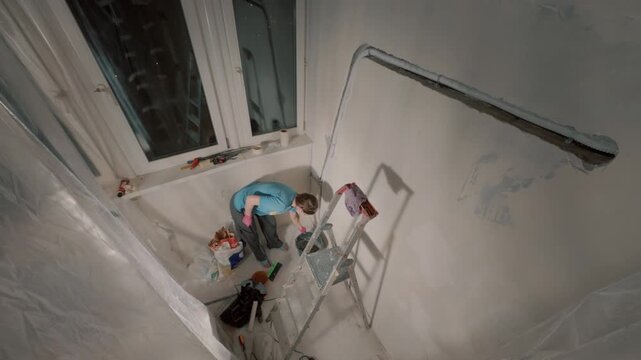 Young woman doing home wall repair near window