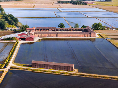 Aerial view of Tenuta Colombara historic farm complex surrounded by flooded rice fields and rural landscapes in Livorno Ferraris, Piemonte, Italy.