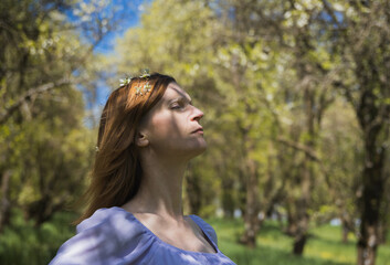 Naklejka premium Portrait of young woman with blossom in brunette hair and closed eye from side. Lifestyle modern people background