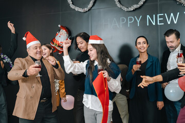 Naklejka premium New year party celebration with smiling adult people, festive hat, wine glass, balloon, and holiday decoration in indoor office event