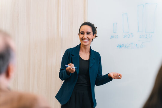 Businesswoman presenting marketing chart in office meeting with smile