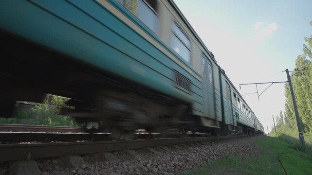 Suburban Electric Train Passing at High Speed: Low Angle Close-Up Side View with Motion Blur | Railway Cars, Track and Overhead Wires on Sunny Day