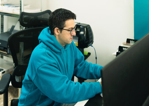 Man wearing hoodie concentrating on computer work