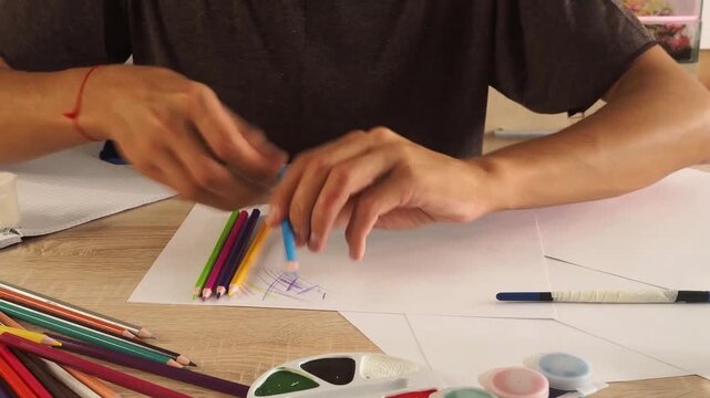 a man draws with pencils on paper 