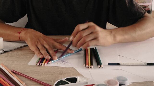 a man draws with pencils on paper 