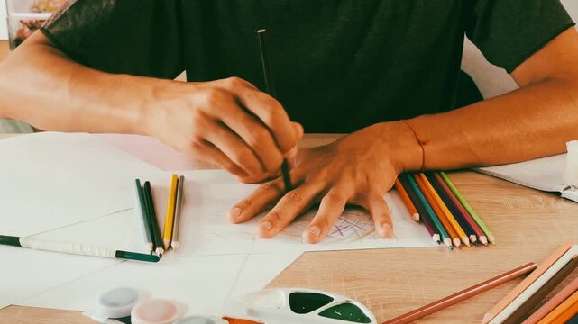 a man draws with pencils on paper 