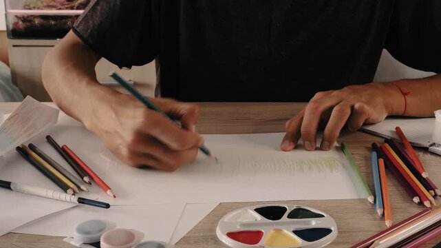 a man draws with pencils on paper 