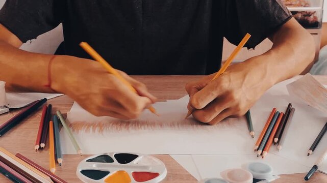 a man draws with pencils on paper 
