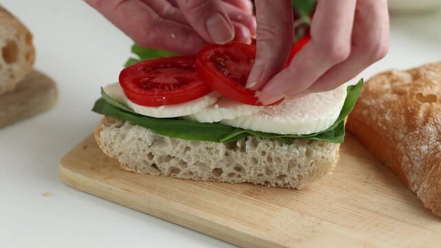 Woman hands cooking healthy panini sandwich with lettuce, mozzarella cheese and tomatoes. Italian style panini sandwich
