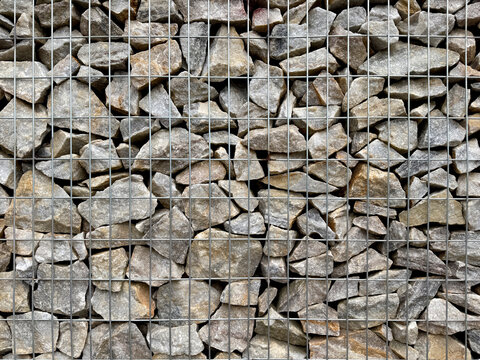 Close up photo of gabion wall, gabion is a series of riprap or rubbles stones, stacked and solidified and confined inside a wiremesh metal to function as a partition or retaining wall structure.