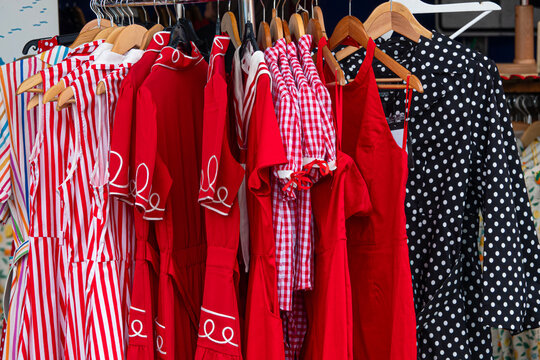 Red dresses hang on racks in a lively market