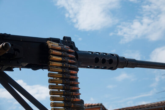 A gun with ammo sits under passing clouds