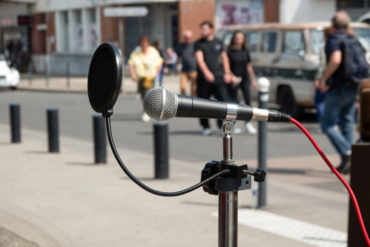 A microphone with a pop filter stands on a street