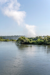Fototapeta premium waterfall mist plume over thik vegetation on superior Igauzu river shores at nature park, Iguazu Waterfalls, Argentina