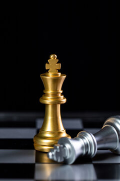 Golden king and fallen silver king on chessboard