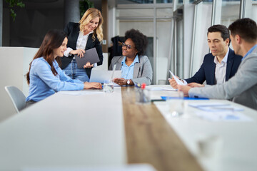 Fototapeta premium Happy businesswoman talking to her colleagues while having a meeting in the office.