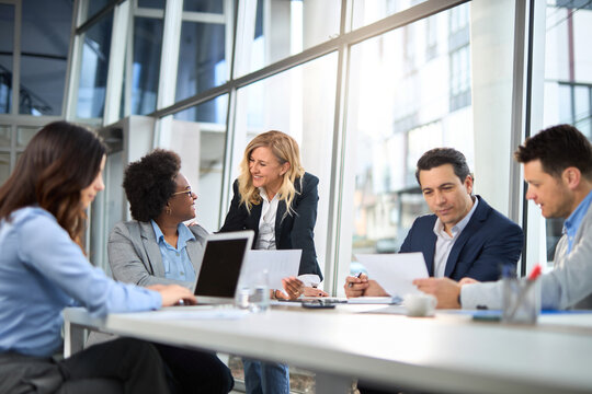 Happy businesswoman talking to her colleagues while having a meeting in the office.