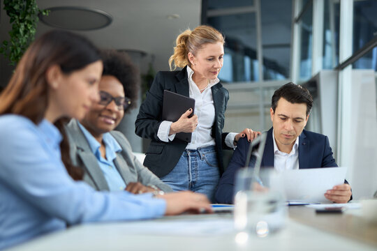 A female CEO discusses business with her employees during a meeting