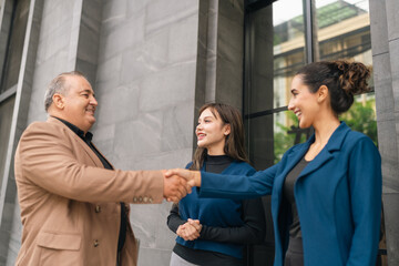 Business handshake outdoors smiling people meeting in front of building professional greeting office exterior teamwork agreement trust partnership cooperation © chokniti