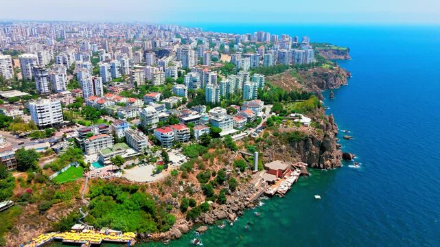 Clifftop neighborhood of low-rise houses and mid-rise apartments, with high-rise buildings further back, near Lower Düden Waterfalls, Antalya, Turkey.