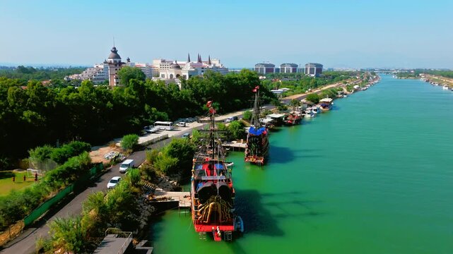 Drone aerial near Antalya, Turkey. Calm turquoise river, canal with boats and waterfront trees, viewed from above.