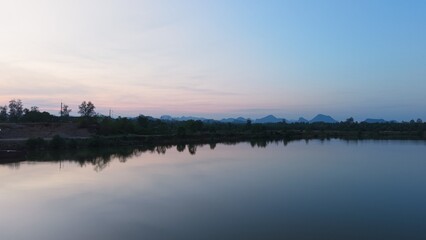 Naklejka premium Landscape sunset over chumphon river, still water reflecting sky and mountains