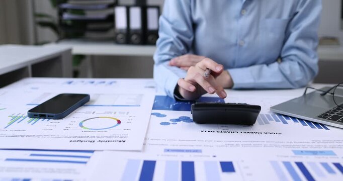 Individual Reviewing Financial Reports.An Asian individual reviews financial reports and property rates, calculating income and expenses with serious dedication using technology.
