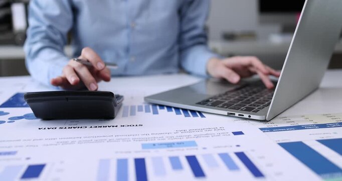 Individual Reviewing Financial Reports.An Asian individual reviews financial reports and property rates, calculating income and expenses with serious dedication using technology.
