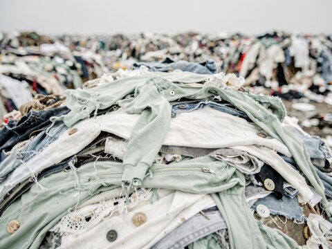 Pile of discarded clothing and textiles at a landfill site for environmental awareness campaigns, sustainable fashion industry reports and waste management news