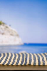Fototapeta premium Minimal summer composition featuring clean sandy beach with empty copy space for product placement. Rocky coastline meets the sea under bright blue sky, creating natural and scenic atmosphere.