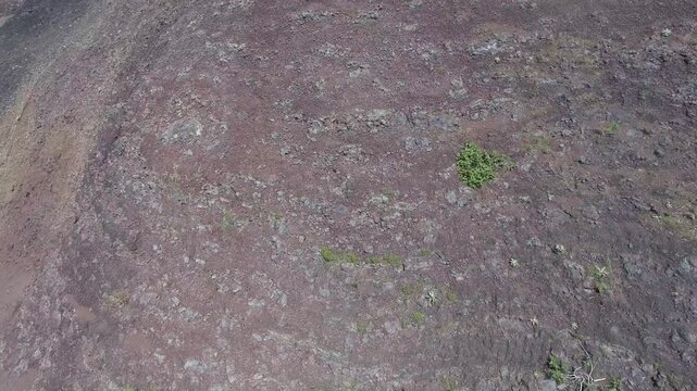 Aerial volcanic tuff cone layers reveal exposed mineral bands and rugged geologic structure. Eroded ash deposits, raw stratification, ancient eruption traces show striking earth history.