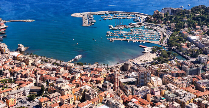 Aerial view of the vibrant harbor and historic town center with colorful buildings and numerous yachts moored in the blue sea at Rapallo, Liguria, Italy.