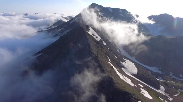 Ural Mountains Russia mountain peaks rise above clouds with rugged ridges and high altitude drama. Misty layers, vapor flow, elevated relief create striking atmospheric scenery across remote ranges.