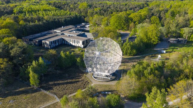 Aerial view of the Radiotelescoop surrounded by dense green forest and research facilities in Dwingeloo, Drenthe, Netherlands.