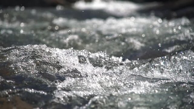 Mountain stream rushes over rocks through alpine terrain with clear fast water and raw energy. Fresh current, stony channel, lively runoff shape a vivid highland creek scene for nature search.